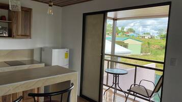 Una cocina con mostrador, refrigerador y comedor con sillas y mesa.