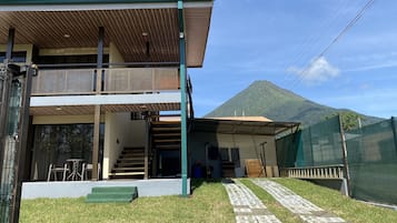 Una casa de dos pisos con un balcón y una escalera que conduce al nivel superior, con una vista de la montaña al fondo.