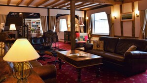 A cozy room with a wooden ceiling, leather furniture, a red carpet, and a bookshelf. - 4 bedroom accommodation in Pulham Market, near Diss (Pulham Market, near Diss)