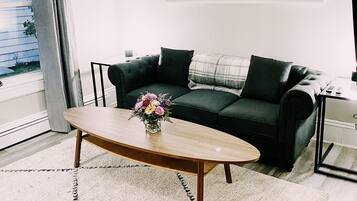 Una sala de estar con un sofá, una mesa de centro y un espejo en la pared.