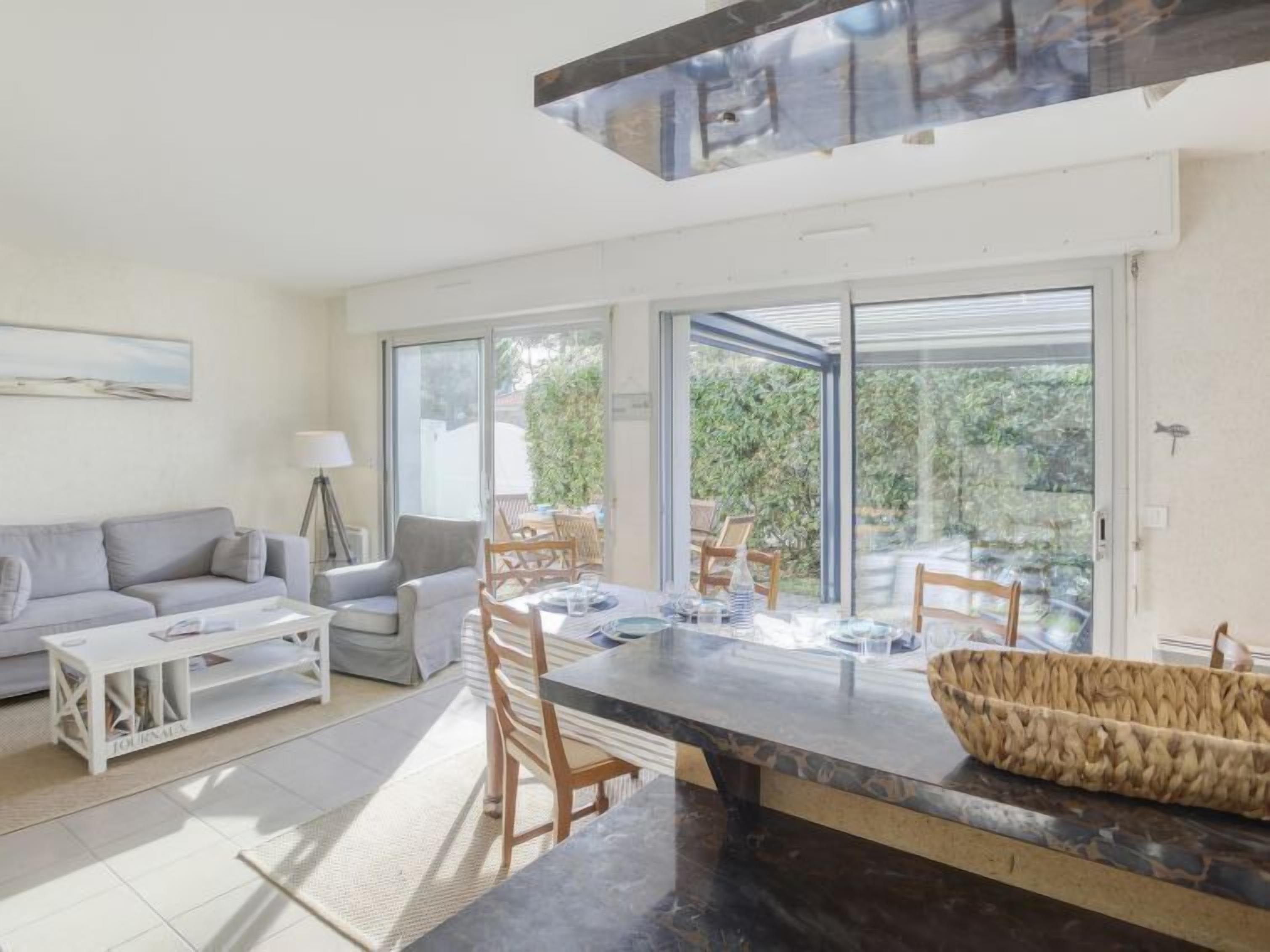 Uma sala de estar moderna com sofá, mesa de centro e área de jantar com cadeiras e mesa.