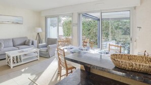 Ein modernes Wohnzimmer mit Sofa, Couchtisch und Essbereich mit Stühlen und Tisch.