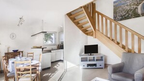 Ein modernes Wohnzimmer mit Essbereich, einer Treppe und einer Küche.