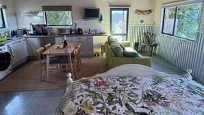 Una habitación compacta con cama, una mesa de comedor, kitchenette y ventana.