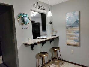 A kitchen area with a 'No Smoking' sign, a 'Cheers' sign above a mirror, and a painting of a beach scene. - Choosy Chisholm Charm (Oklahoma City)