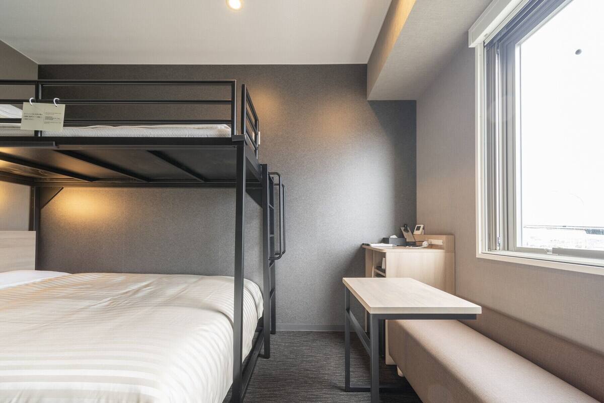 Een slaapkamer met stapelbed, bureau en een bank.