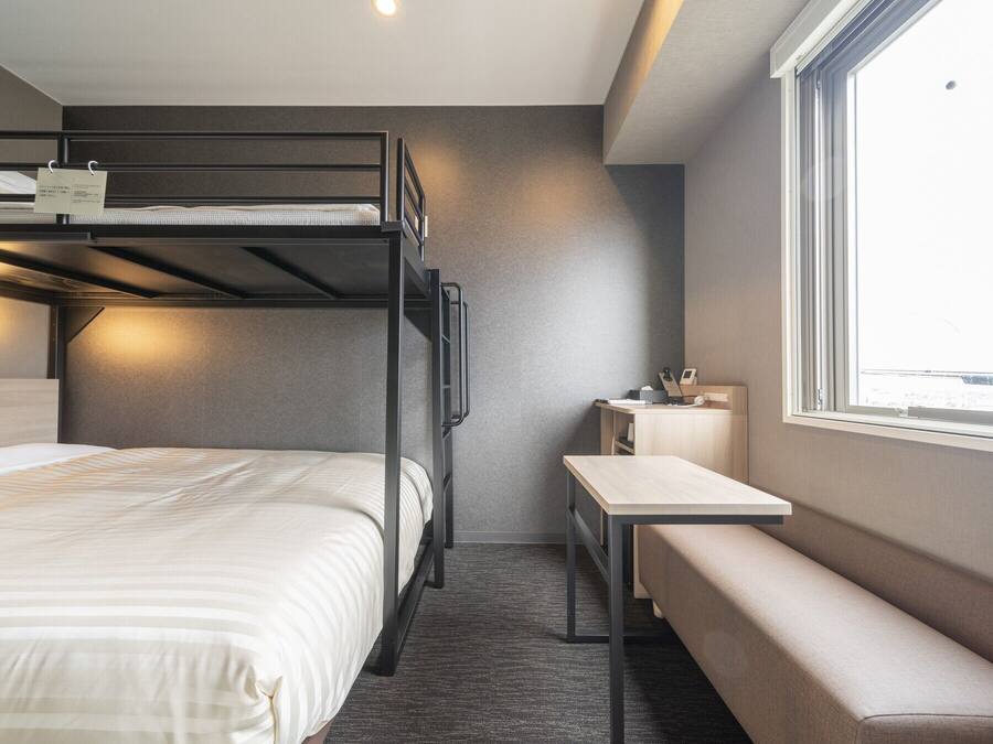A bunk bed room with a desk and a bench.