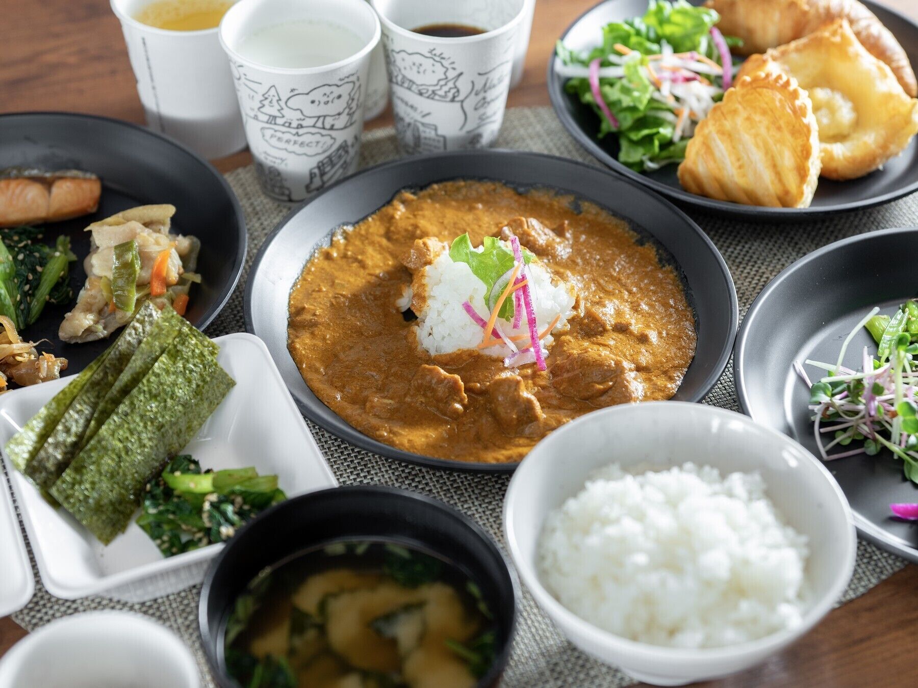 Variedad de platos que incluyen curry, arroz y verduras sobre una mesa.