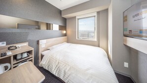 A hotel room with a bed, a desk with a phone and a kettle, a mirror, and a window with a city view. - Super Hotel Kanku Kumatoriekimae (Kumatori)
