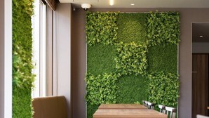 A restaurant interior with a green wall, wooden tables, and a bench. - Super Hotel Kanku Kumatoriekimae (Kumatori)