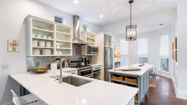 Una cocina moderna con armarios blancos, electrodomésticos de acero inoxidable y una isla central.