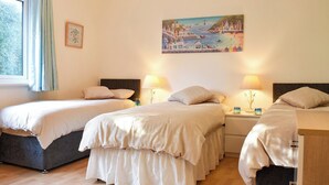 A hotel room with two beds, a painting of a coastal scene, and a window with curtains. - 3 bedroom accommodation in Ryde (Ryde)