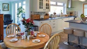 A kitchen with white cabinets, a dining table set with plates, cups, and a potted plant. - 3 bedroom accommodation in Ryde (Ryde)