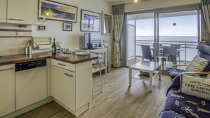 Cocina compacta con comedor y balcón con vistas al mar.