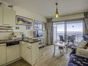 Une cuisine compacte avec un coin repas et un balcon offrant une vue sur la mer.