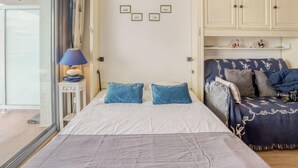 Un dormitorio con cama, mesita de noche, lámpara, armario y sofá.
