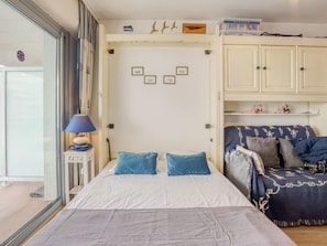 Une chambre à coucher comprenant un lit, une table de chevet, une lampe, une armoire et un canapé.