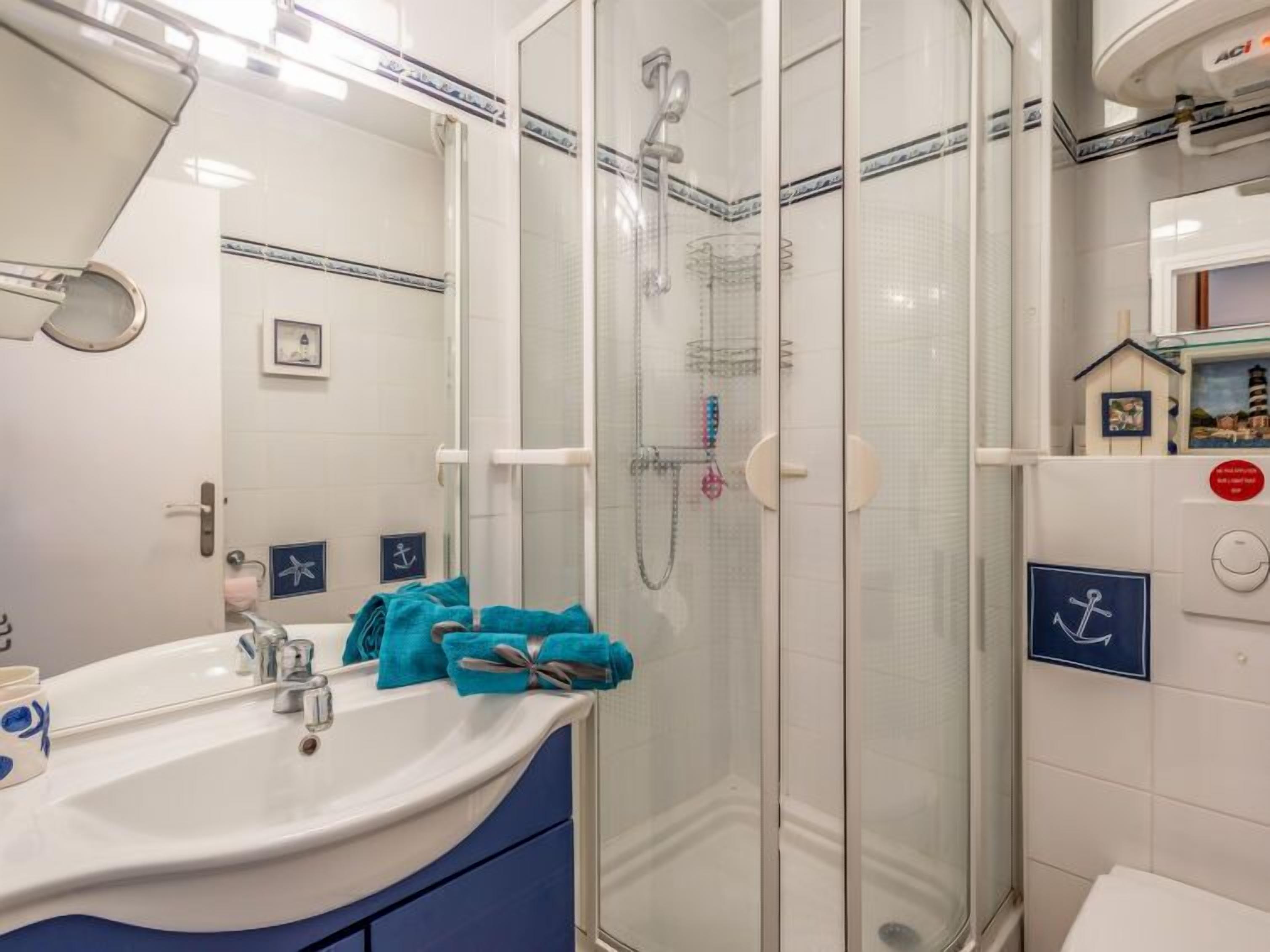 A bathroom with a glass-enclosed shower, a sink with a mirror, and a toilet.