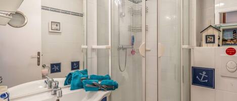 A bathroom with a glass-enclosed shower, a sink with a mirror, and a toilet.