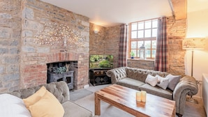 A cozy living room with a stone fireplace, a television, a sofa, and a wooden coffee table. - 2 bedroom accommodation in Wrantage, near Taunton (Wrantage, near Taunton)