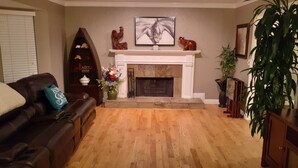 A living room with a fireplace, a brown leather sofa, a wooden coffee table, and a potted plant.