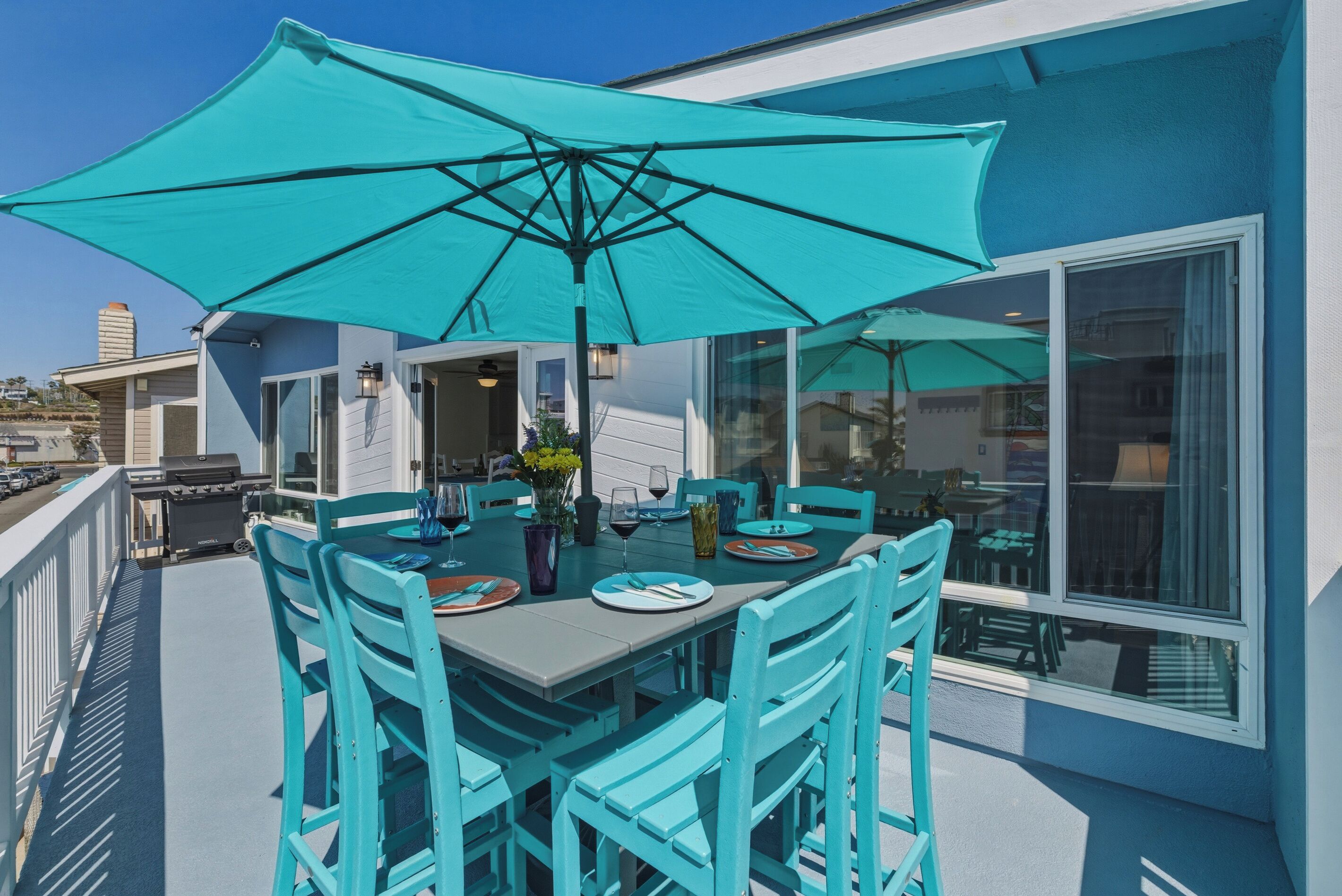 A dining area with a table, chairs, and a large umbrella.