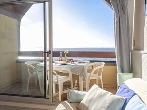 A balcony with a table set for two, overlooking the sea.