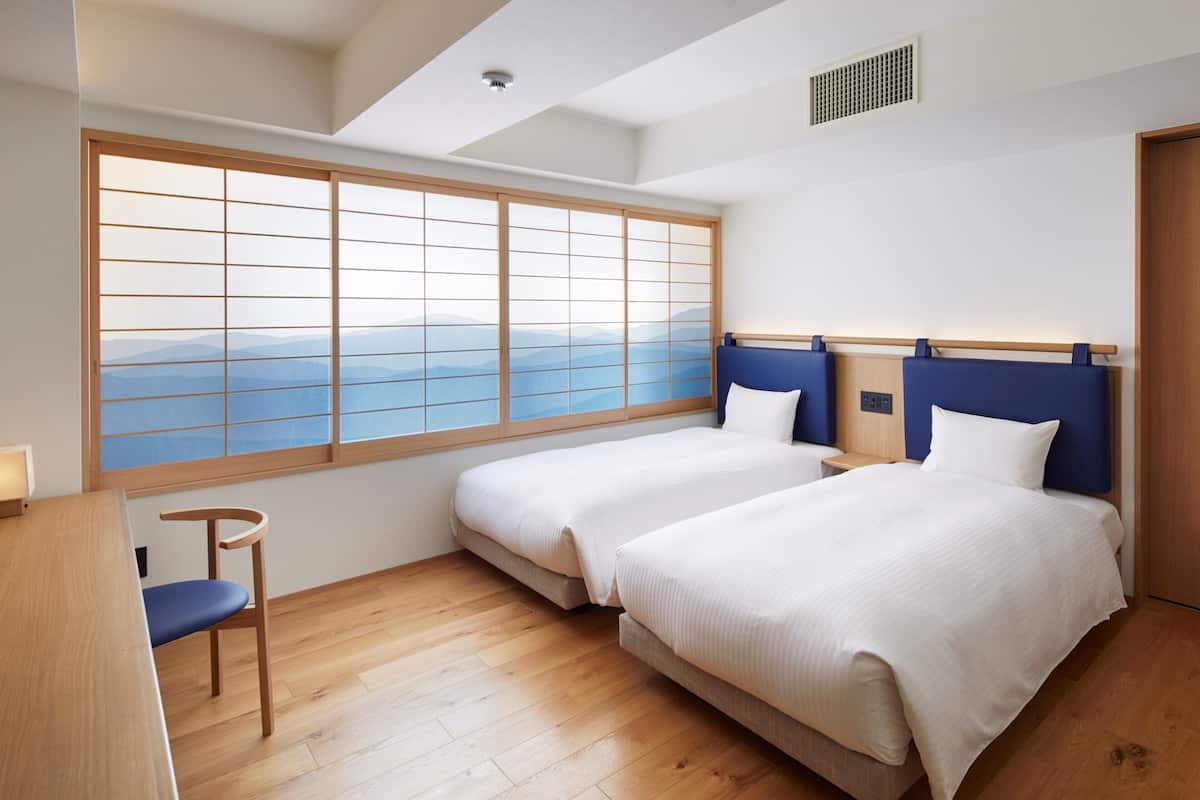 Une chambre d’hôtel avec deux lits, un bureau et une chaise.