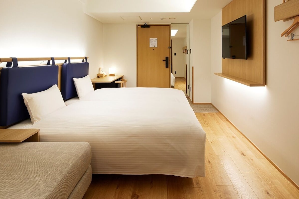 Ein Hotelzimmer mit einem großen Bett, Nachttischen, einem an der Wand montierten Fernseher und einem Holzboden.