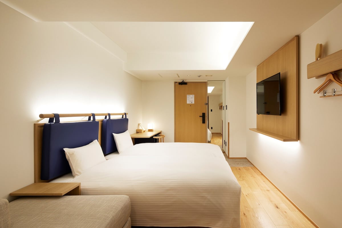 Une chambre d’hôtel avec un lit, un canapé, un téléviseur fixé au mur et un plancher en bois.