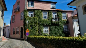 Un edificio con fachada rosa y hiedra verde cubriendo las paredes.