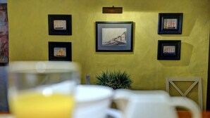 Un comedor con pared amarilla, una obra de arte enmarcada y una planta en maceta.