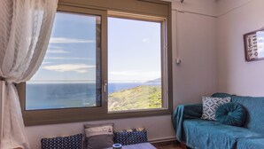 A room with a large window, a sofa, a table with a tray, and a curtain.