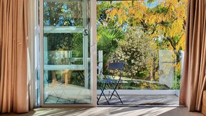 A room with a sliding glass door leading to an outdoor area with autumn foliage.