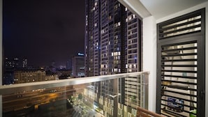 Een balkon met uitzicht op hoge gebouwen in de nacht.