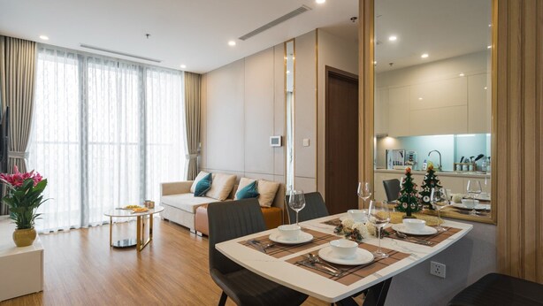 Een moderne eetruimte met een tafel voor vier personen, een bank en een keuken op de achtergrond.