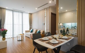 Een moderne eetruimte met een tafel voor vier personen, een bank en een keuken op de achtergrond.