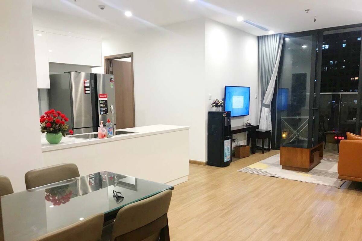 A modern living room with a glass dining table, a sofa, and a TV.