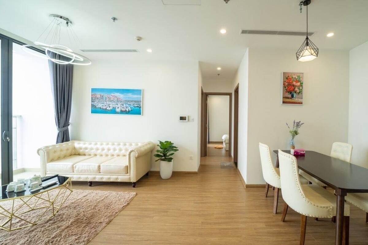 A modern living room with a sofa, a dining table with chairs, a coffee table, and a potted plant.
