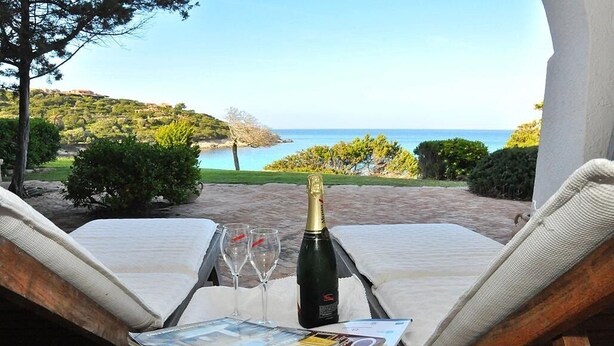 A balcony with two lounge chairs, a bottle of champagne, two glasses, and a magazine. - Sea Front "House in the House" - Porto Cervo Costa Smeralda (Porto Cervo)