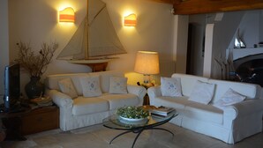 A living room with two white sofas, a glass coffee table with a plant, a lamp, and a sailboat decoration on the wall. - Sea Front "House in the House" - Porto Cervo Costa Smeralda (Porto Cervo)