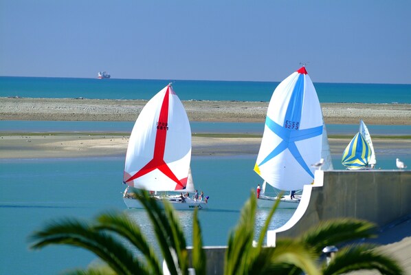 Two sailboats on a calm sea with a beach in the background.