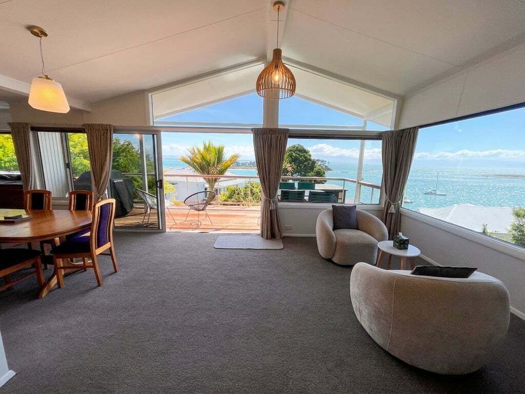 Une pièce spacieuse comprenant un coin repas, un espace salon et une grande fenêtre donnant sur la mer.