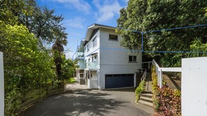 A residential building with a garage, surrounded by lush greenery and a clear sky. - Kimberley Three - Nelson Waterfront Apartment - Free Cancellation Available Here (Nelson)