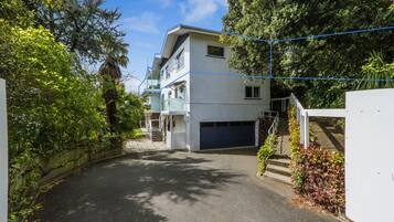 A residential building with a garage, surrounded by lush greenery and a clear sky.
