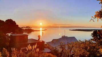 A coastal view with a sunset, calm water, and buildings in the foreground.