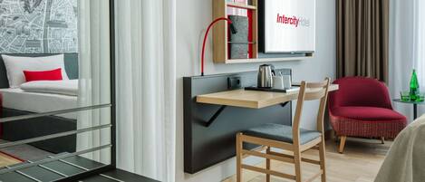 Een moderne hotelkamer met een bed, een bureau met stoel, een televisie en een kaart aan de muur.