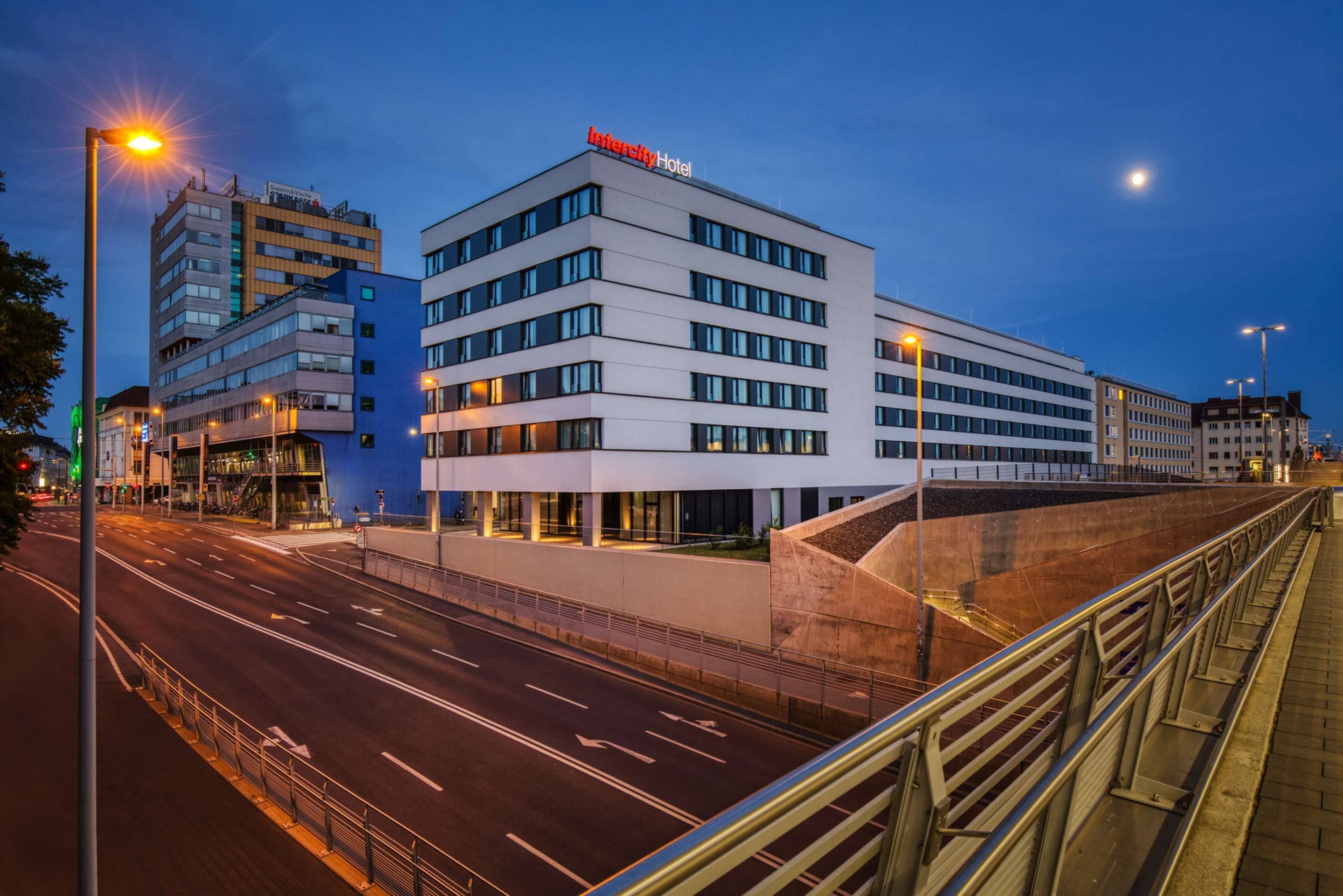 A modern hotel with a prominent sign, multiple floors, and a well-lit facade.