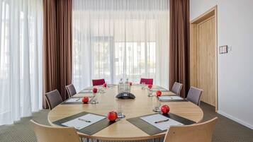 Ein Konferenzraum mit rundem Tisch, Stühlen und einem Projektor.
