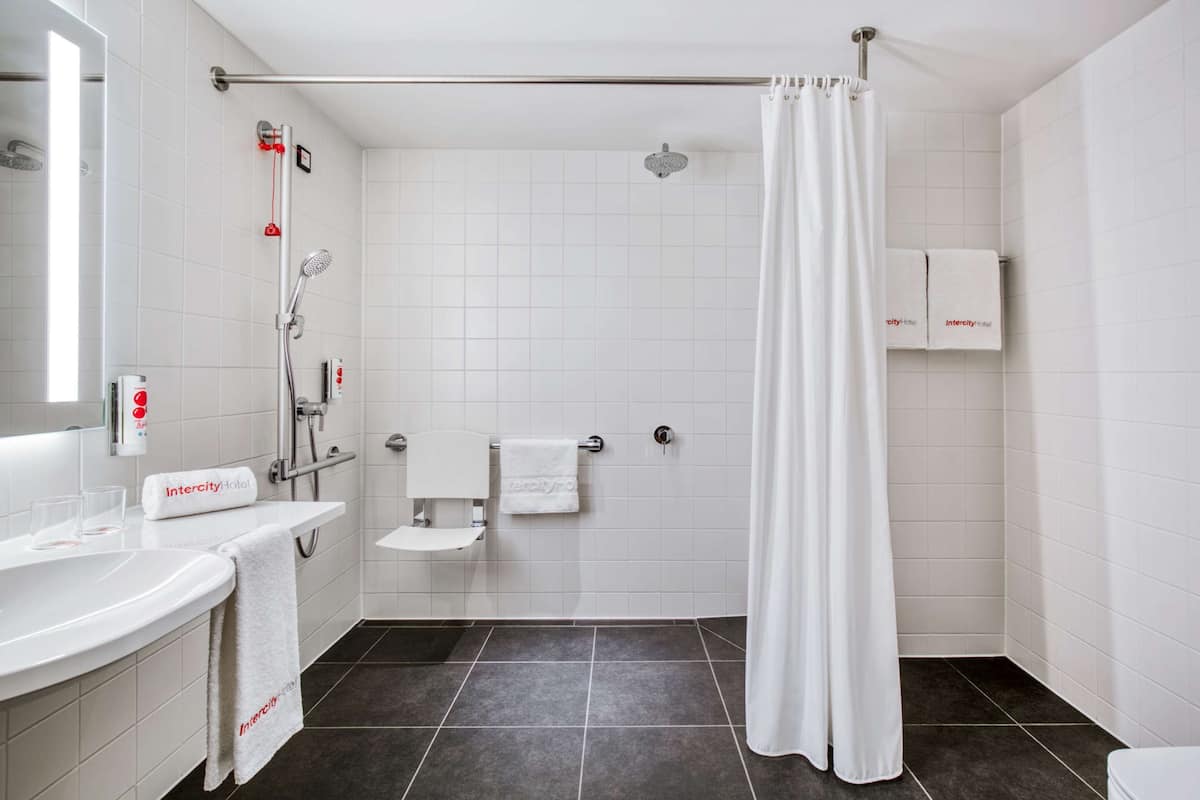 Un baño moderno con ducha, inodoro y lavamanos. Hay toallas colgadas en la pared y una cortina de ducha.
